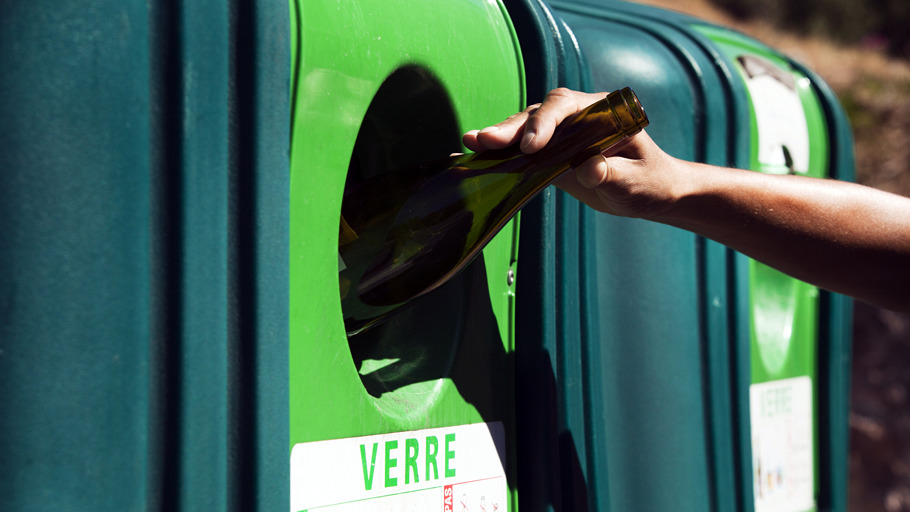 Bouteille en verre jetée dans un conteneur de recyclage verre